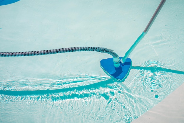 Swimming pool cleaning tools in the bottom of the pool. Clear water in the pool.