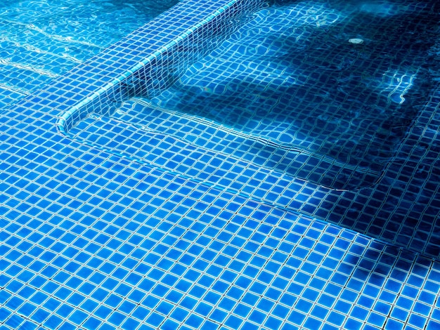 Swimming pool steps with clear water surface background nobody Abstract pool texture underwater pattern blue background with grid tiles no people Overhead view Summer background