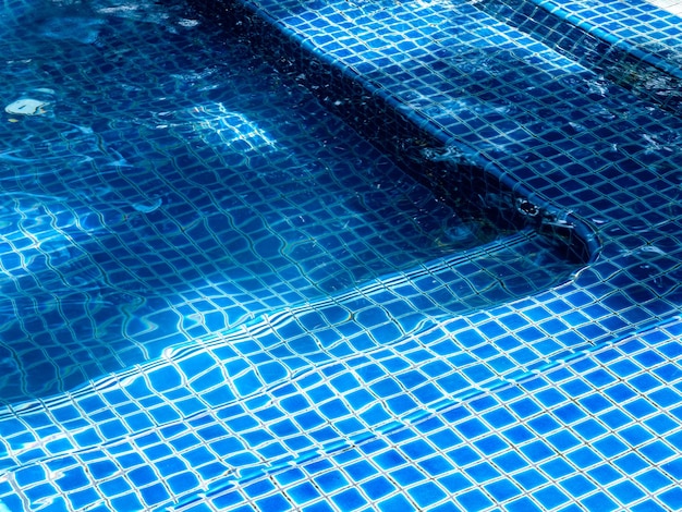 Swimming pool steps with clear water surface background nobody Abstract pool texture underwater pattern blue background with grid tiles no people Overhead view Summer background