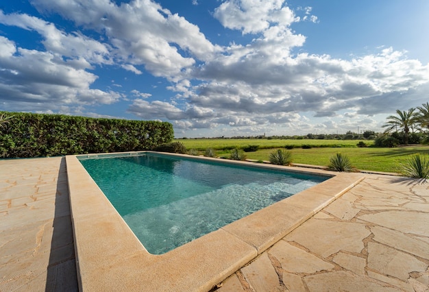 Swimming pool with views over green garden with blue cloudy skies