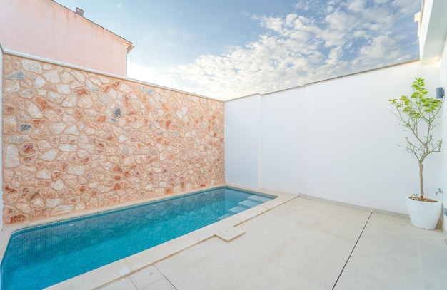 Swimming pool with a white and natural stone wall in a terrace