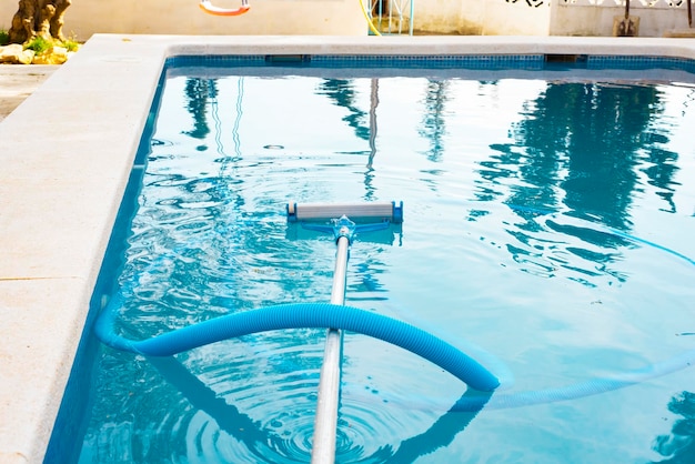 A swimming pool without people with a hose and a mop a vacuum cleaner for cleaning the pool