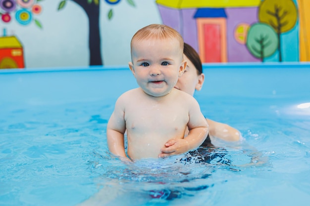 A swimming teacher teaches a little boy to swim in the pool Children's first swimming lessons Development for babies