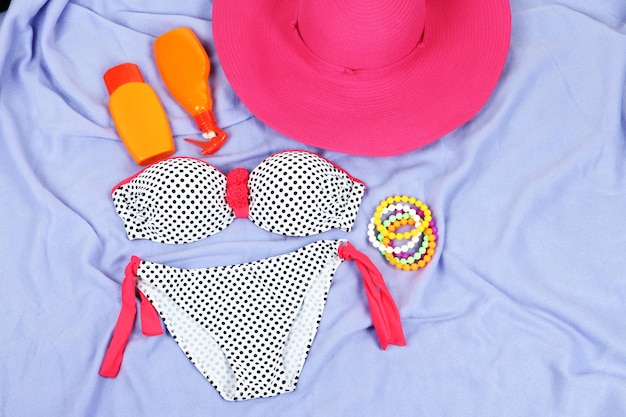 Swimsuit and beach items on purple background