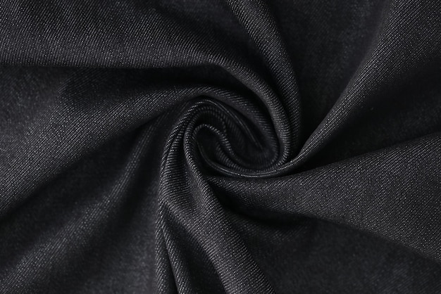 Swirled gray denim fabric as background wavy black jeans textile closeup