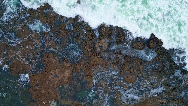 Swirling water foaming coast cliffs zoom out stormy ocean crashing of stones