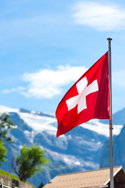 Swiss flag against Alps mountains Vertical shot with a selective focus