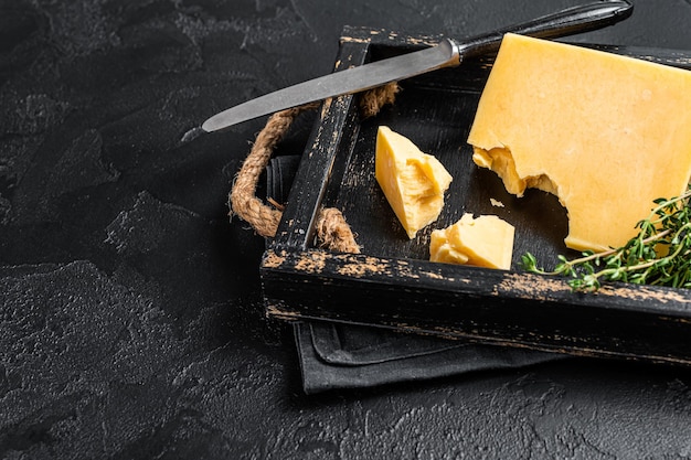 Photo swiss hard cheese piece in wooden tray. black background. top view. copy space.