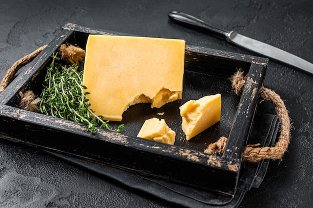 Photo swiss hard cheese piece in wooden tray. black background. top view.