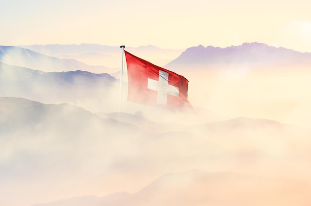 Photo switzerland flag disappears in beautiful clouds with fog