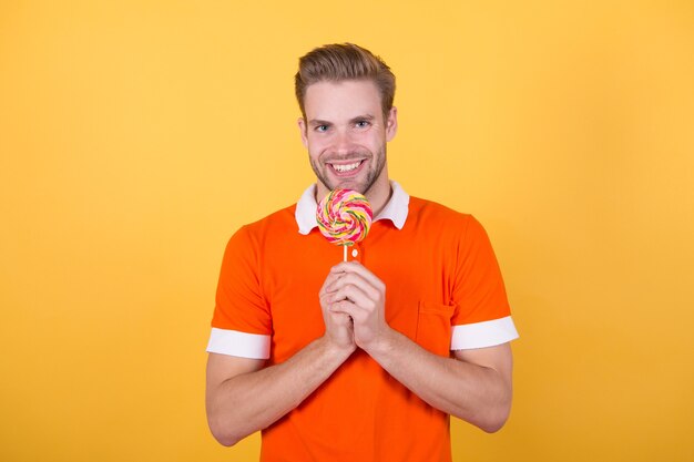 Symbol of happiness. Man eat sweet lollipop. Man smiling hold lollipop. Cheat meal concept. Sugar harmful for health. Guy hold lollipop candy yellow background. Taste of childhood. Holiday tradition.