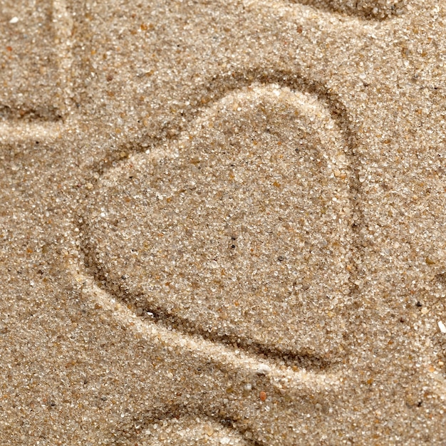 Photo the symbol of heart is drawn on clean sand