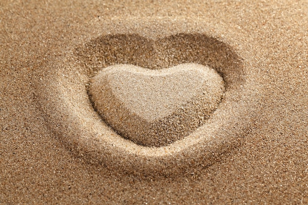 Photo the symbol of heart is drawn on clean sand