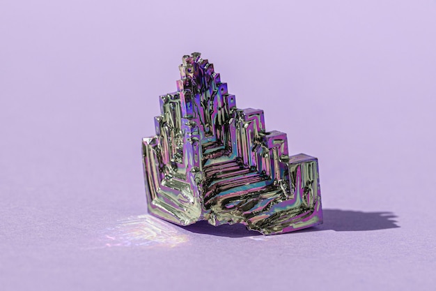 Synthetic bismuth Bismuthum crystal with iridescent oxide film on pink background close up isolated Amazing colorful shiny rainbow Bismuth Gemstone mineral Banner