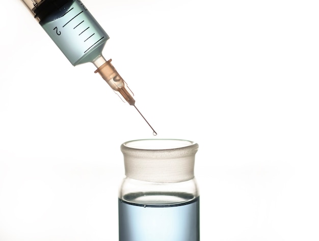 A syringe and a glass flask with a blue liquid, a photo on the topic of medicine and scientific research.