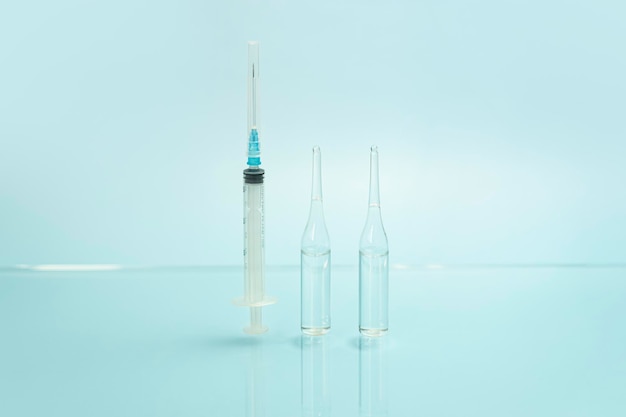 Syringe and glass vials with a clear liquid on a blue background the concept of medicine and health