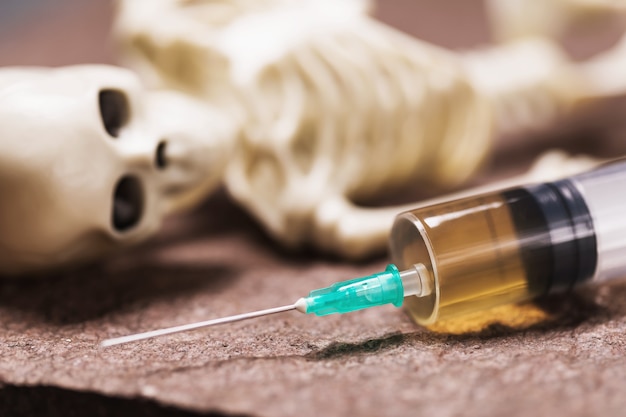 Syringe and human skeleton on a stone lethal injection concept