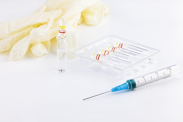 Syringe for injection on the background of ampoules with injection medicine and medical gloves