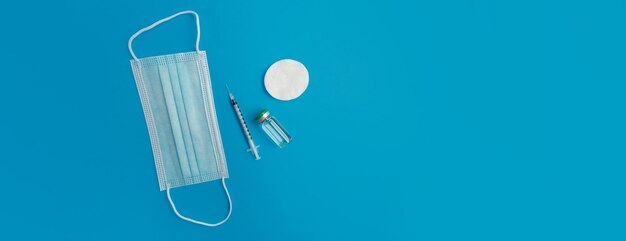 Syringe medical mask and ampoule with medicine on a blue panorama background