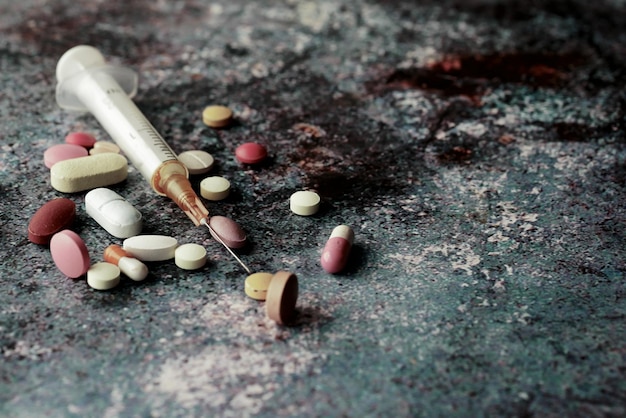 Syringe and pills on dark background close up