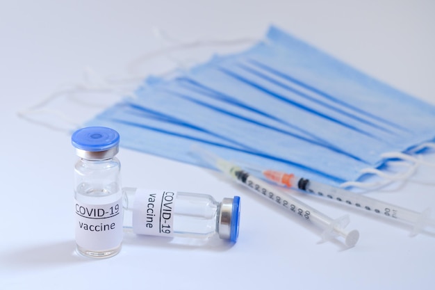 syringe with medical masks and vaccine vial glass bottles for vaccination. COVID-19. Coronavirus