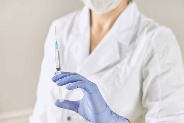 Syringe with a medicine in the hand of a nurse in a white coat