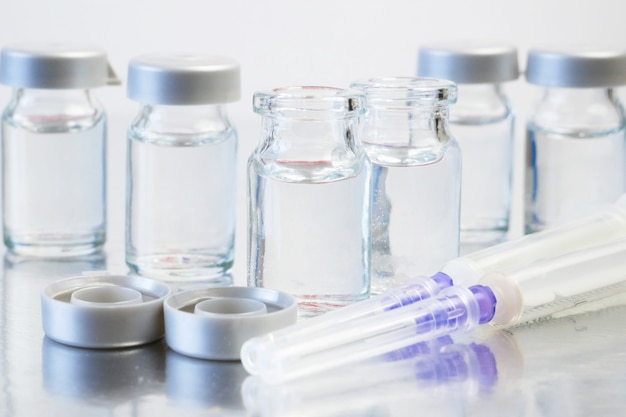 syringes and bottles of covid-19 vaccine, closeup