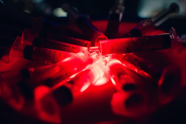 Syringes with blood clearance Halloween horrible on a dark background with red lighting