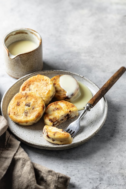 Syrniki or cottage cheese fritters with chocolate poured with condensed milk in the process of eating on ceramics plate