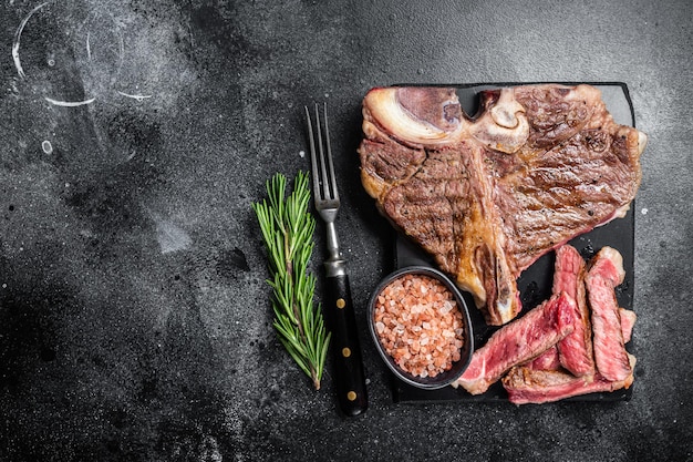 T bone grilled beef meat Steak cooked Porterhouse on a marble board Black background Top view Copy space