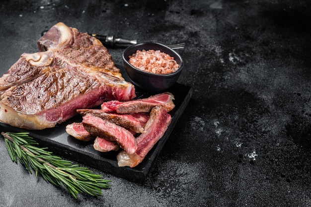 T bone grilled beef meat Steak cooked Porterhouse on a marble board Black background Top view Copy space