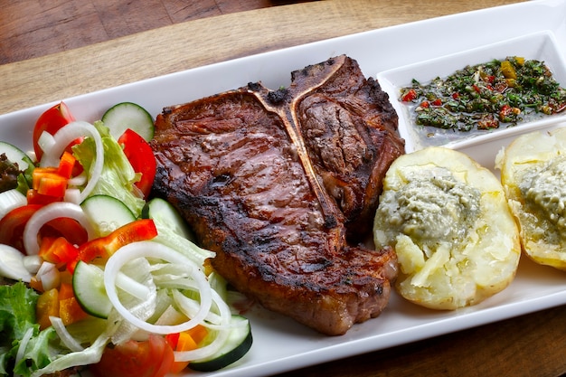 T bone steak with potato salad and vegetables