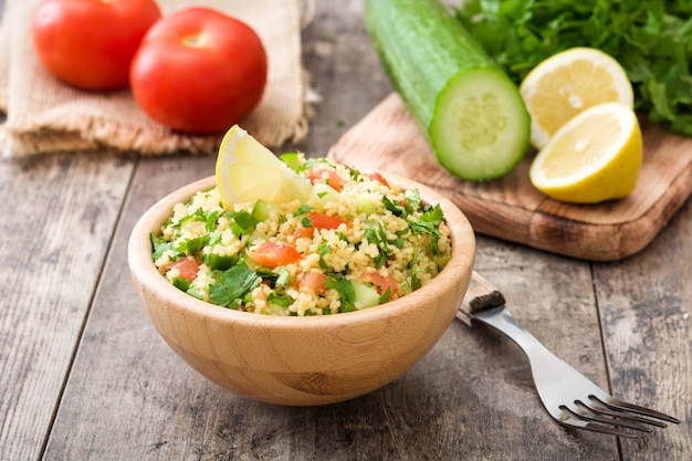 Tabbouleh salad with couscous in wooden bowl on rustic table