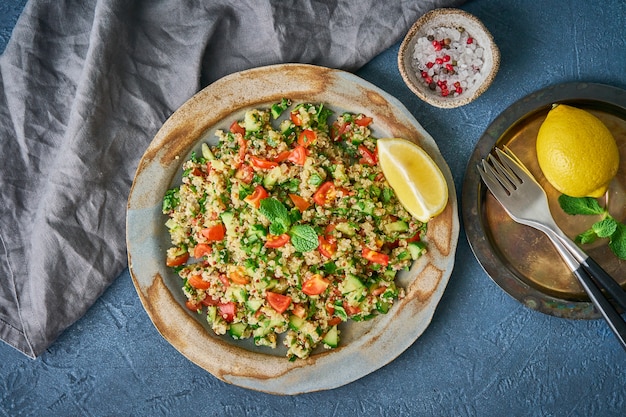 Tabbouleh salad with quinoa. Eastern food with vegetables mix on dark