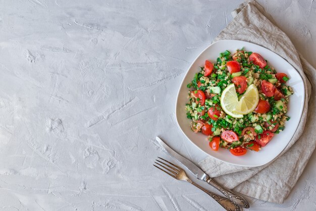 Tabbouleh Tabouli salad on dish on light gray concrete. Top view