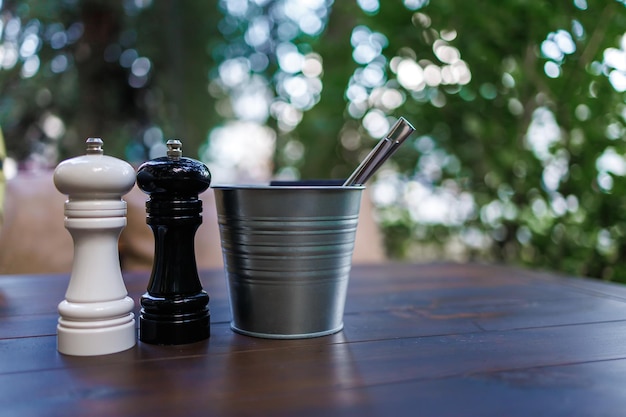 On the table in the cafe appliances a bucket of ice and a pot of salt and pepper