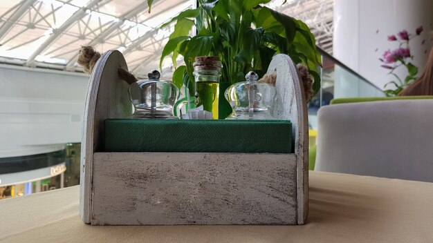 A table in a cafe or restaurant. Napkins in a wooden napkin holder, spices salt and pepper, olive oil and sauce on the table.