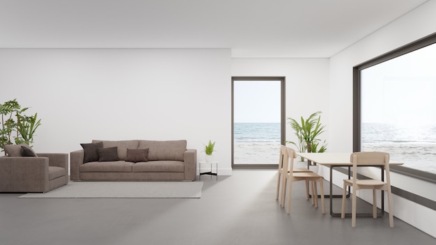 Table on concrete floor of large dining room near living area and sofa in modern beach house or luxury hotel.