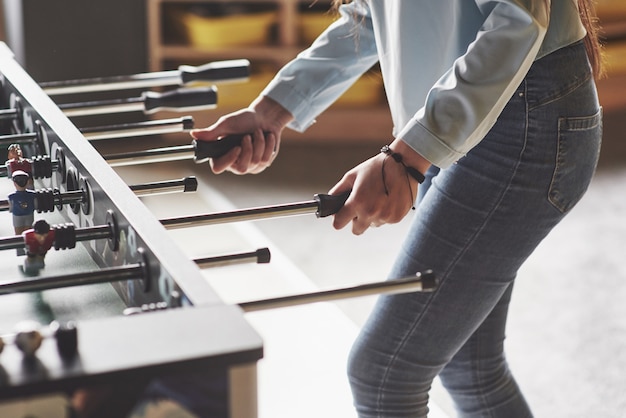 Table football in the entertainment center. Beautiful girl playing football