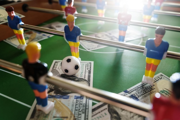 Table football game with US dollar bills scattered around it alluding to a betting concept