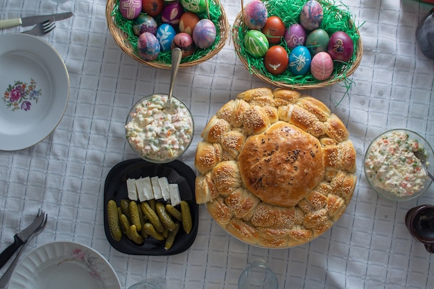 Table full of food on easter holyday. Colored eggs and bread shoot from upper angle