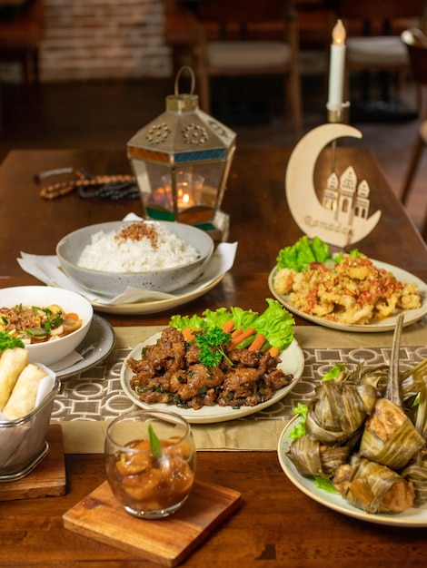 A table full of food including a plate of food and a lantern with the words ramadan on it.