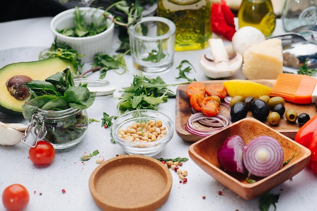 A table full with ingredients for salad Olives onion greens oil pine nuts