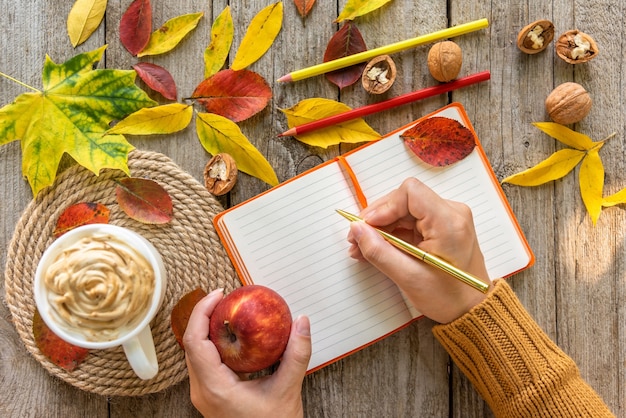 On the table is a notebook on an autumn morning with a Cup of coffee