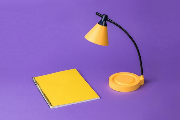 A table lamp with a yellow notebook on a purple background Desktop lighting