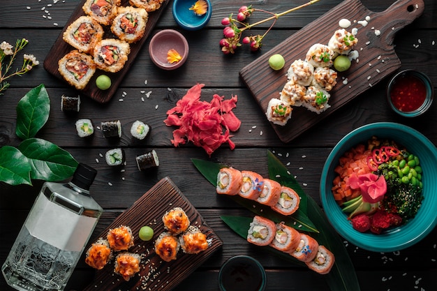 Table served with sushi, rolls and traditional japanese food on dark background. Top view.