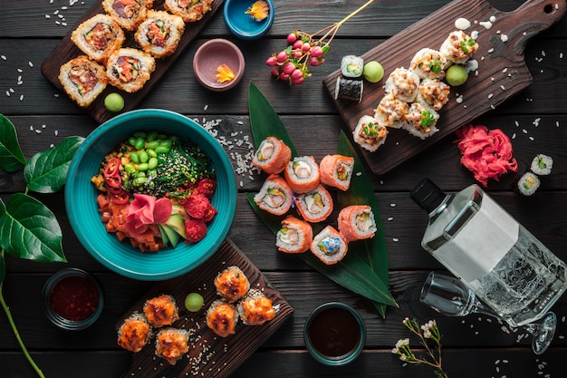 Table served with sushi, rolls and traditional japanese food on dark background. Top view.