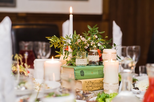 Table set at the wedding Banquet in the restaurant, classic style with white tablecloths and napkins, vases with flowers.