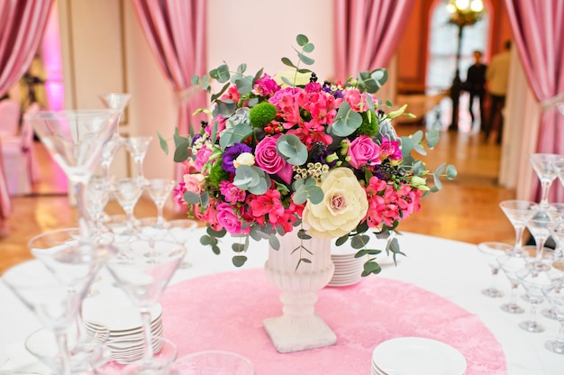 Table set at the wedding Banquet in the restaurant, classic style with white tablecloths and napkins, vases with flowers.