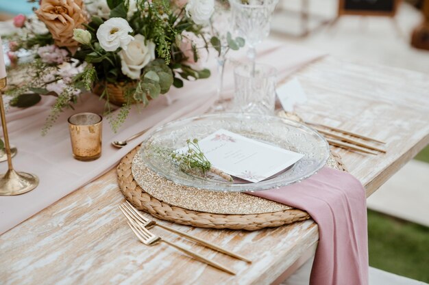 Photo a table set for a wedding with a pink tablecloth and a place setting with a white card on it.